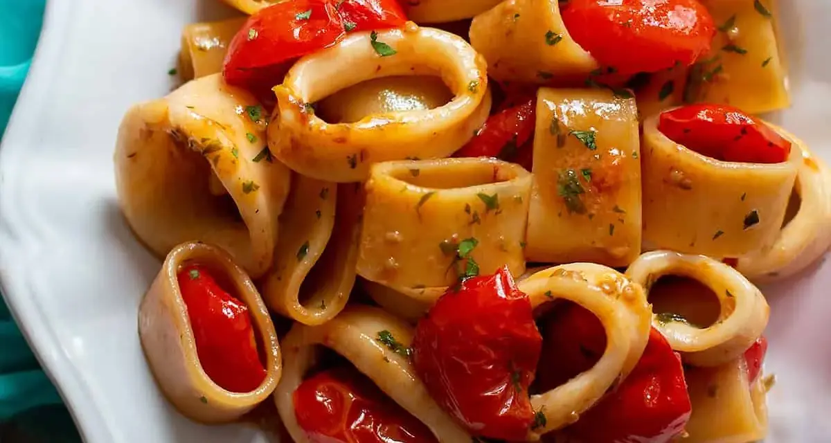 Un invitante sugo di pesce con anelli di calamaro e pomodorini, guarnito con prezzemolo fresco.