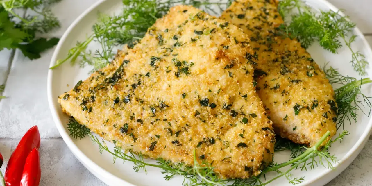 Due filetti dorati di pesce spada alla palermitana, croccanti e profumati, adagiati su un letto di finocchietto fresco.