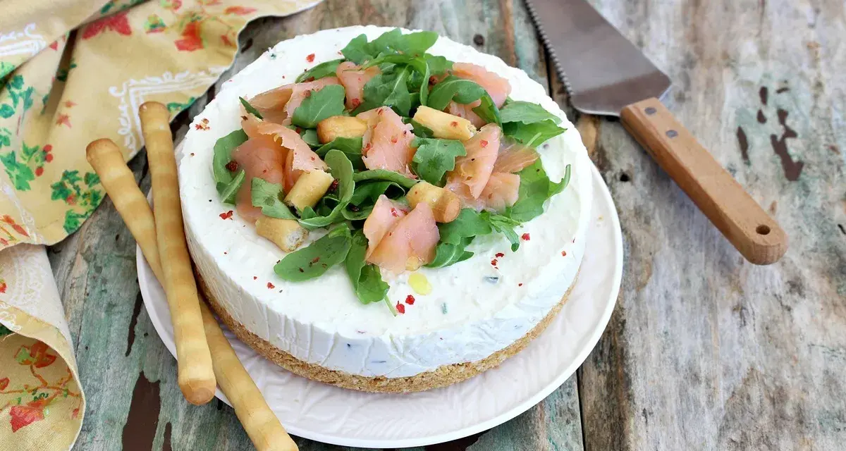Deliziosa cheesecake salata con salmone affumicato, rucola e crostini. Perfetta per un aperitivo o antipasto elegante.