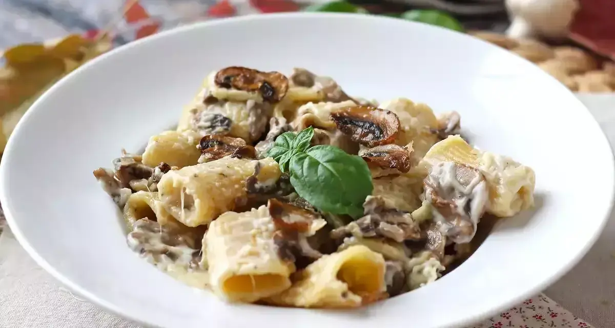 Piatto invitante di pasta panna e funghi, guarnito con basilico fresco.