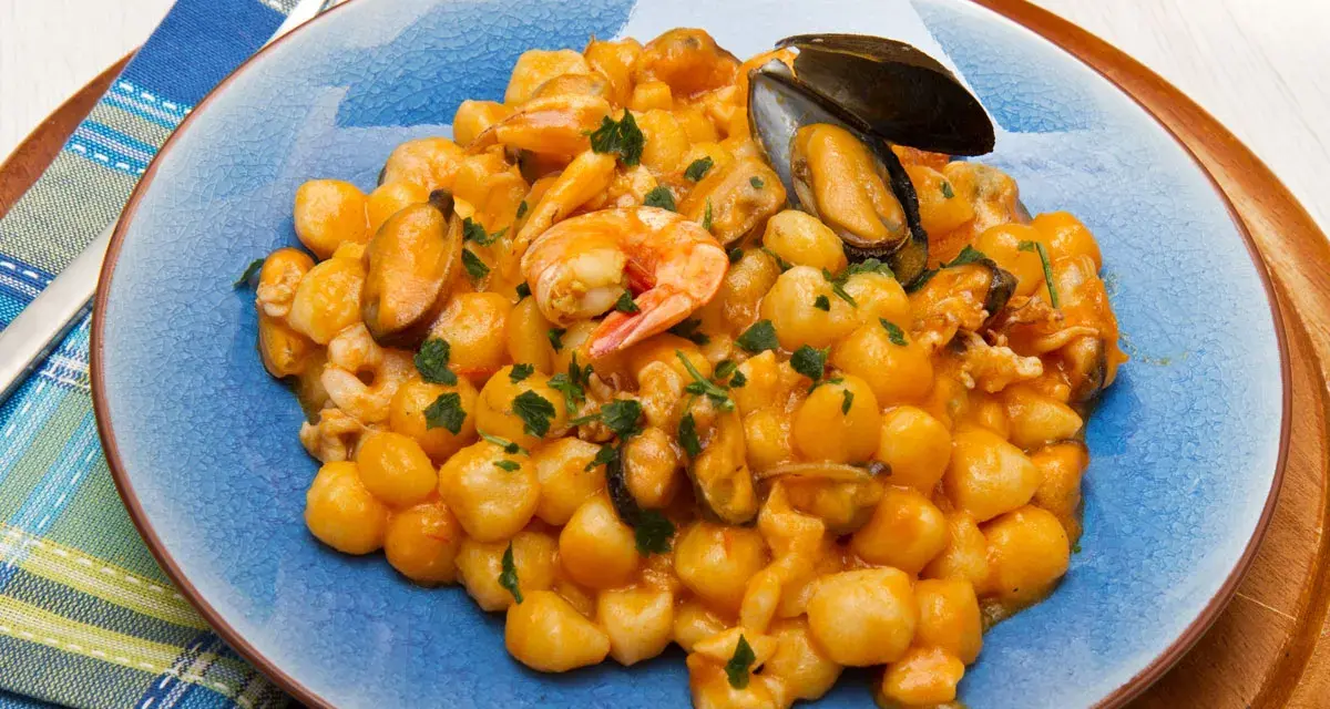 Gnocchi di patate con frutti di mare, gamberi e cozze, guarniti con prezzemolo fresco.