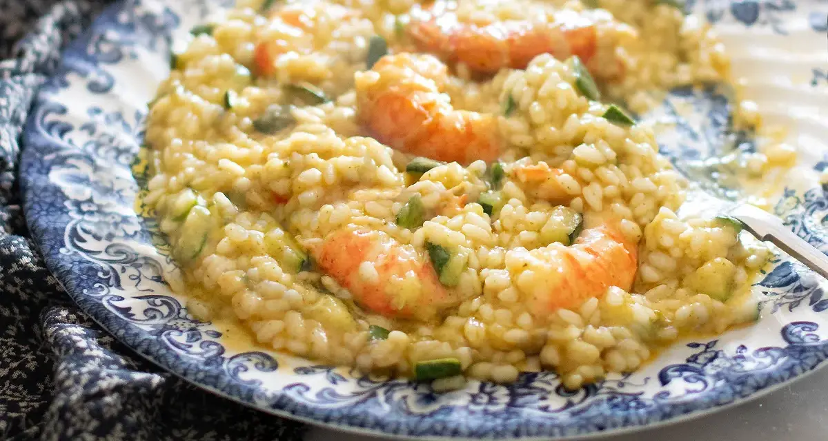 Un cremoso risotto zucchine e gamberetti, servito su un piatto decorato.