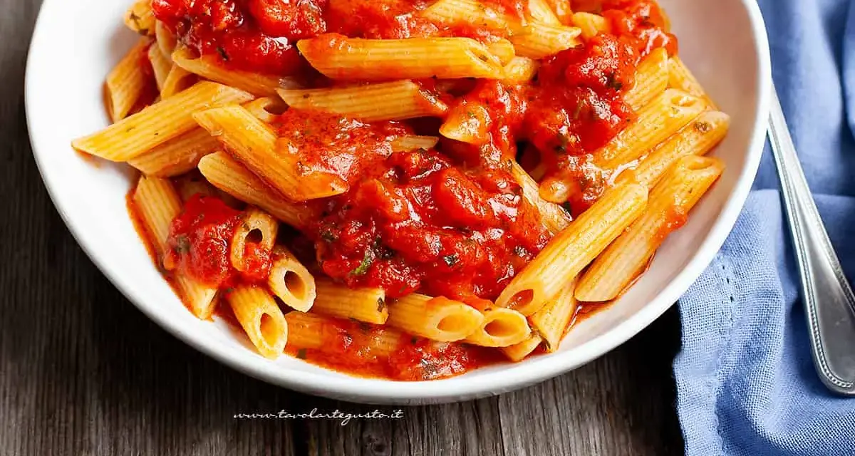 Piatto invitante di penne all'arrabbiata, con la pasta condita da un sugo rosso piccante e saporito.