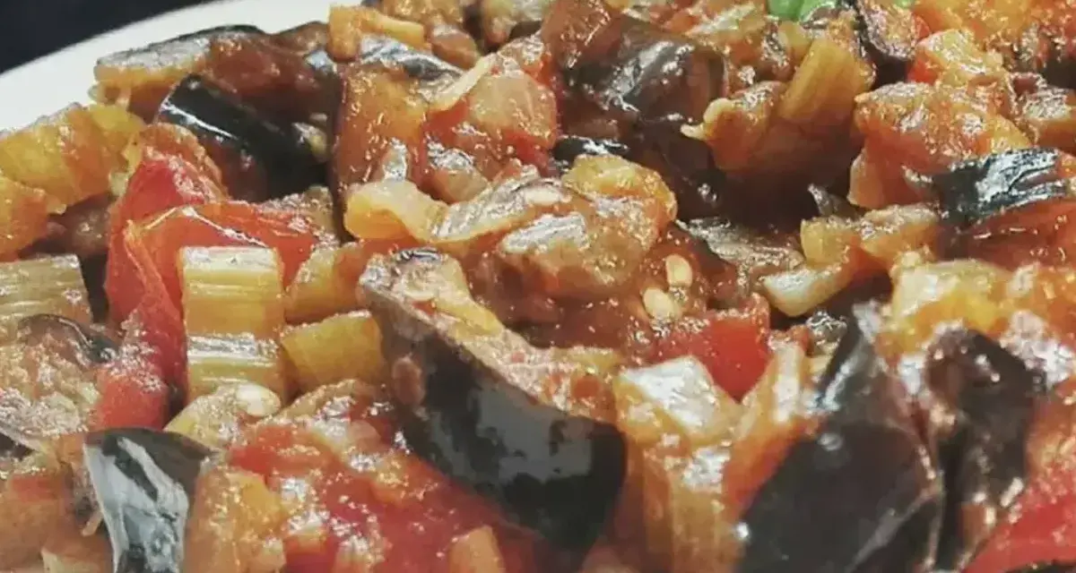 Un primo piano di una saporita caponata siciliana, con melanzane, pomodori e sedano cotti a puntino.