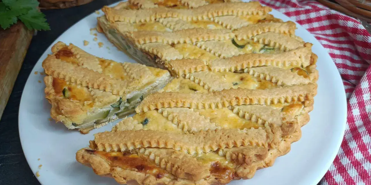 Una deliziosa crostata salata con zucchine e formaggio, con una griglia di pasta dorata e un pezzo tagliato.