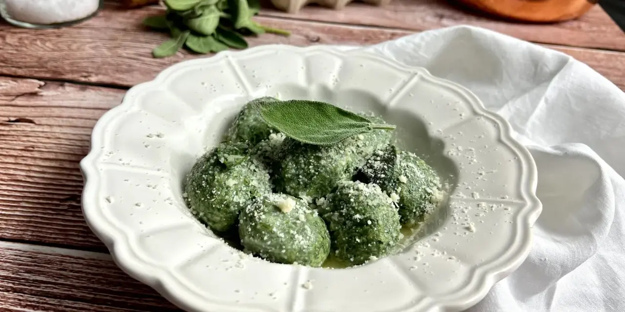 Gnudi verdi, una deliziosa ricetta con spinaci e ricotta, guarniti con parmigiano e una foglia di salvia.