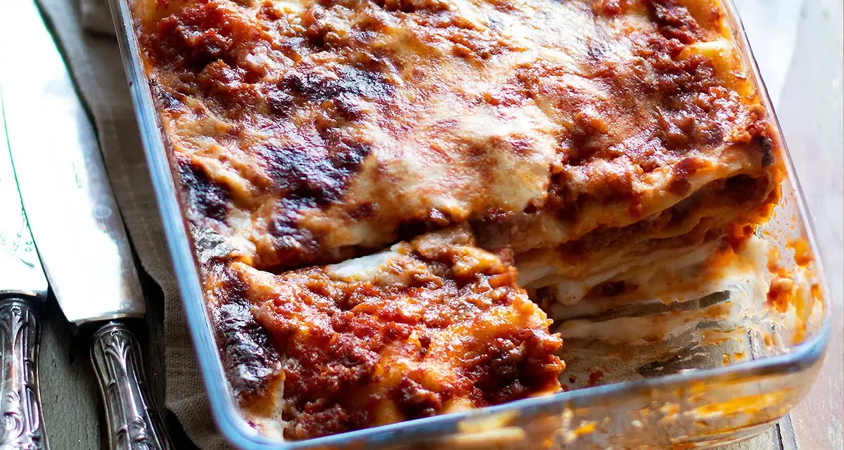 Lasagna alla bolognese appena sfornata, con strati dorati e ripieno succulento, pronta per essere gustata.