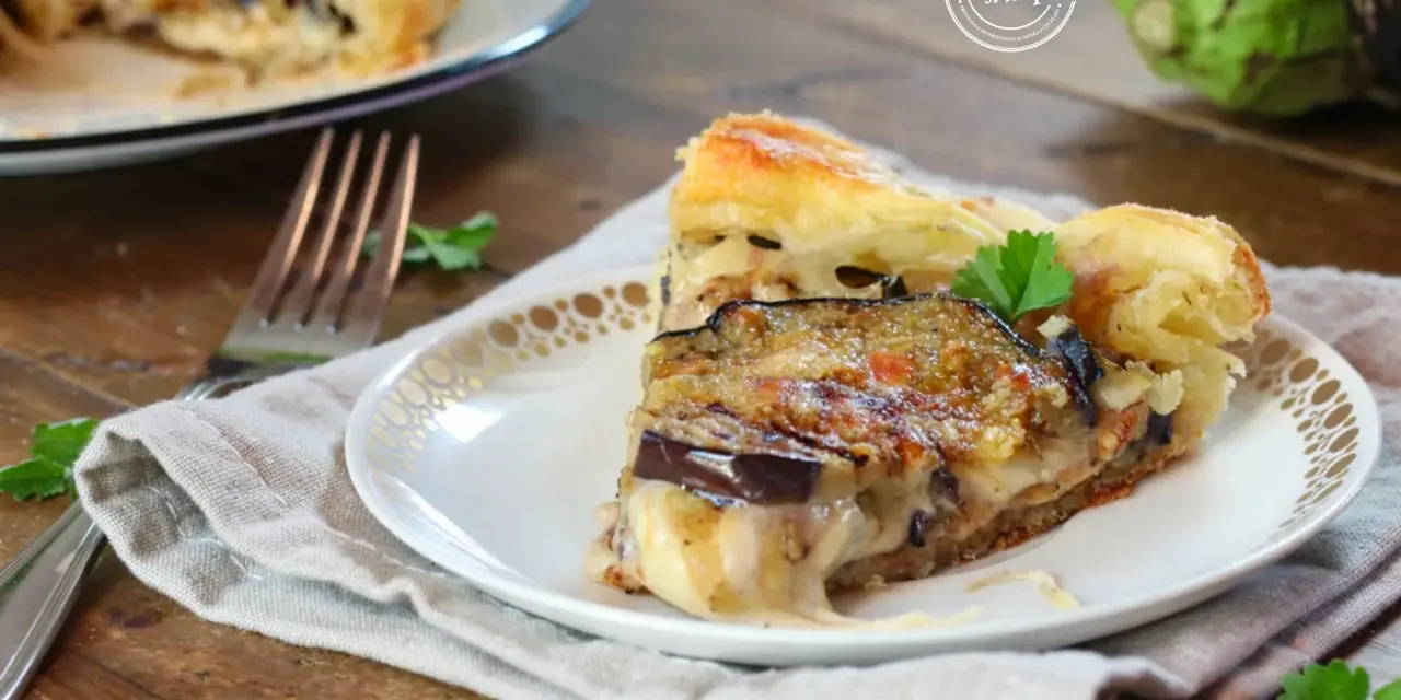 Una fetta di torta salata con melanzane, formaggio filante e pasta sfoglia dorata, guarnita con prezzemolo fresco.