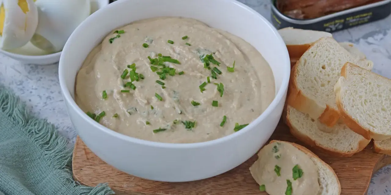 Una cremosa salsa tonnata con maionese, guarnita con erba cipollina, pronta per essere gustata con pane tostato e uova sode.