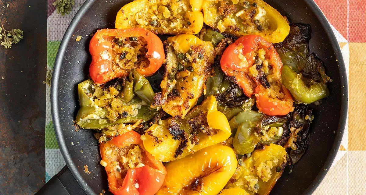 Peperoni ammollicati cotti in padella, ripieni di pangrattato e erbe aromatiche, con colori vivaci.