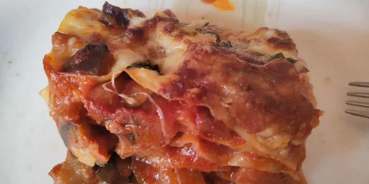 Una fetta di lasagna di melanzane, ricca e saporita, con strati di melanzane, pomodoro e formaggio filante.