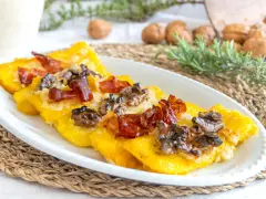 Deliziosi crostini di polenta freddi con prosciutto croccante e noci, un antipasto rustico e saporito.