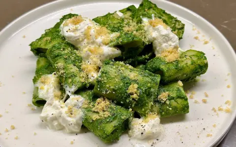 Paccheri conditi con un vibrante pesto di cavolo nero, arricchiti da ricotta cremosa e una spolverata di pangrattato croccante.