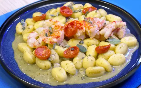 Gnocchi con pesto, gamberi succulenti e pomodorini confit. Un piatto che celebra i sapori del mare e della terra.