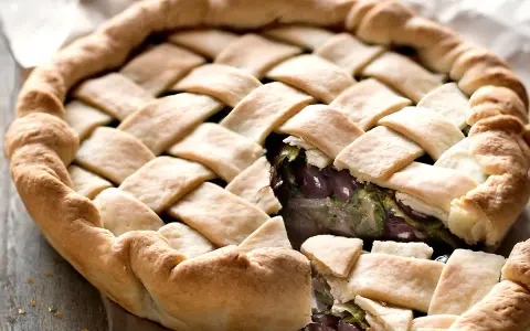 Pizza di scarola con un intreccio dorato di pasta e un ripieno invitante di verdure e olive.