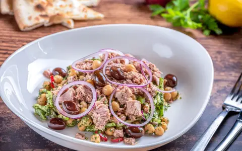 Deliziosa insalata di ceci e tonno con olive nere, cipolla rossa e prezzemolo fresco. Un piatto leggero e gustoso.