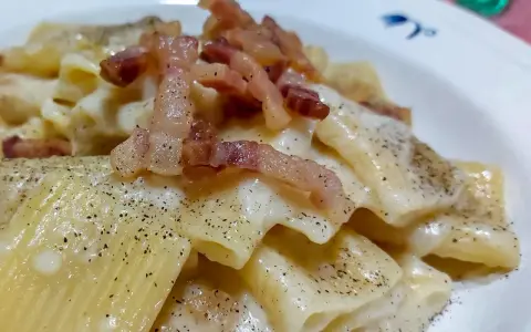 Un piatto di pasta alla gricia fumante, con guanciale croccante e abbondante pepe nero.