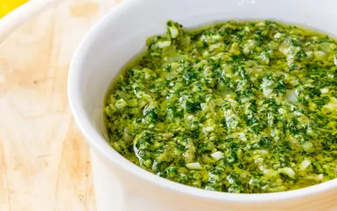Una ciotola bianca piena di vibrante salsa verde, perfetta per accompagnare i tuoi piatti. Questa ricetta salsa verde è un'esplosione di freschezza.