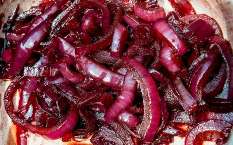 Cipolla rossa caramellata, lucida e succosa, pronta per arricchire ogni piatto con il suo sapore dolce e intenso.