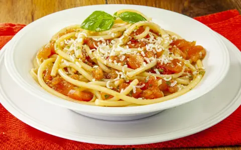 Un piatto invitante di pasta alla carrettiera, con pomodoro fresco, basilico e formaggio grattugiato.