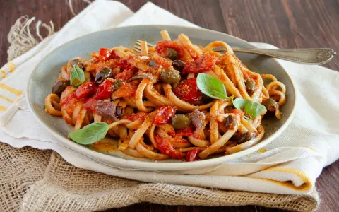 Pasta con sugo rosso, olive, acciughe e basilico, un assaggio di **stroncatura calabrese**.