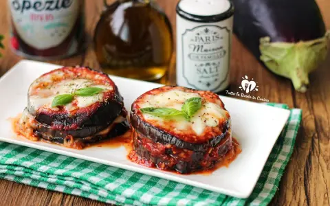 Deliziosa parmigiana di melanzane grigliate, con strati di melanzane, sugo e formaggio filante, guarnita con basilico fresco.