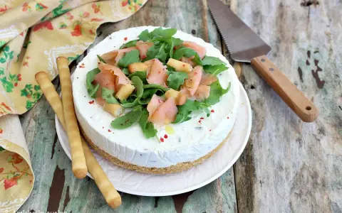 Deliziosa cheesecake salata con salmone affumicato, rucola e crostini. Perfetta per un aperitivo o antipasto elegante.
