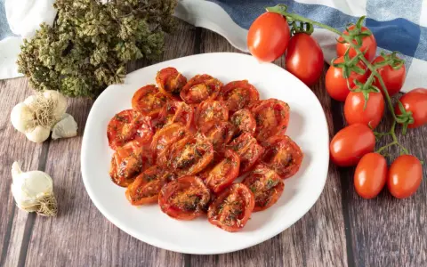 Pomodorini confit in friggitrice ad aria, conditi con erbe aromatiche e aglio. Un contorno saporito e facile da preparare.