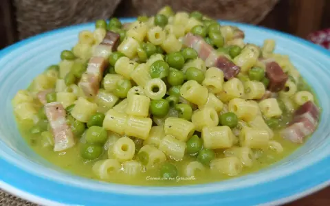 Un piatto invitante di pasta e piselli con cubetti di pancetta croccante, condito con una salsa cremosa.