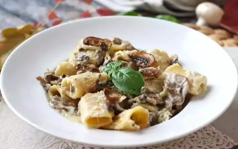 Piatto invitante di pasta panna e funghi, guarnito con basilico fresco.
