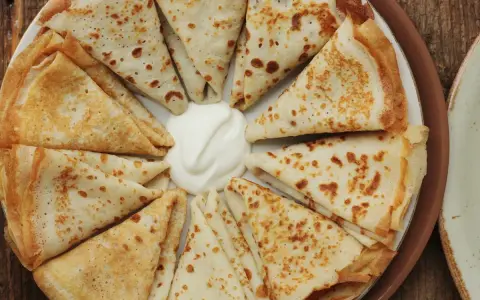 Crespelle piegate a spicchi, con al centro una generosa cucchiaiata di panna acida. Un'idea su crespelle come farcirle per un pasto delizioso.