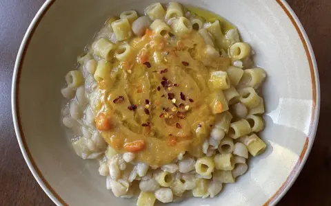 Un piatto di pasta e fagioli estiva, con ditalini e fagioli cannellini, guarnito con una purea di verdure e peperoncino.
