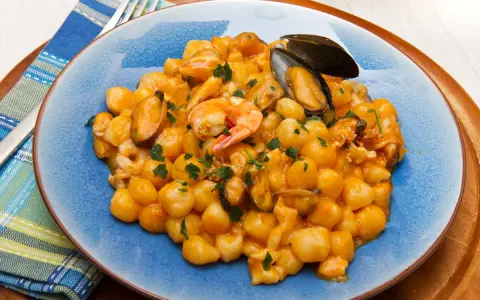 Gnocchi di patate con frutti di mare, gamberi e cozze, guarniti con prezzemolo fresco.