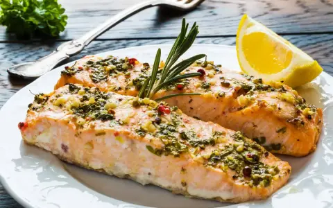 Delizioso salmone al forno con erbe aromatiche, aglio e un tocco di limone, pronto per essere gustato.