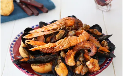 Un piatto ricco di zuppa di cozze, scampi e polpo, servito con pane tostato.