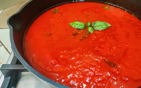 Sugo di pomodoro fresco in padella, profumato con basilico. La ricetta della nonna per un sapore autentico.