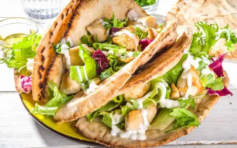 Pita ripiena di pollo e insalata fresca, condita con una cremosa salsa yogurt.