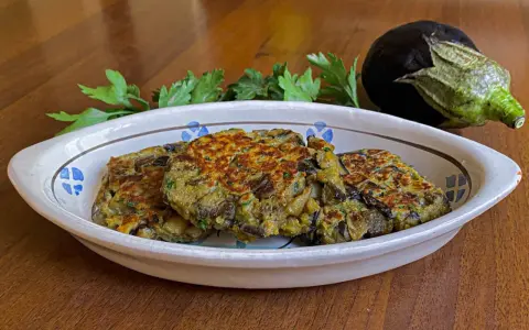 Tre deliziosi hamburger di melanzane dorati, guarniti con prezzemolo fresco, in un piatto rustico.