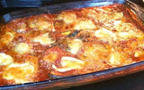 Un invitante pasticcio di melanzane appena sfornato, con strati dorati di formaggio fuso e salsa rossa.