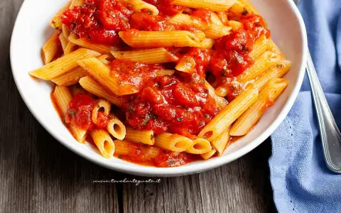 Piatto invitante di penne all'arrabbiata, con la pasta condita da un sugo rosso piccante e saporito.