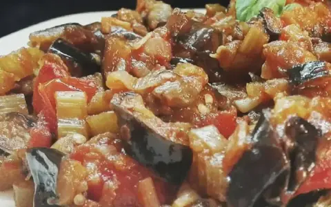 Un primo piano di una saporita caponata siciliana, con melanzane, pomodori e sedano cotti a puntino.