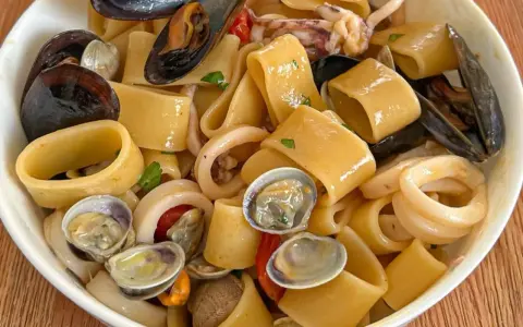 Calamarata allo scoglio ricca di cozze, vongole e anelli di calamaro, un piatto di mare invitante.