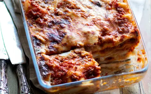 Lasagna alla bolognese appena sfornata, con strati dorati e ripieno succulento, pronta per essere gustata.
