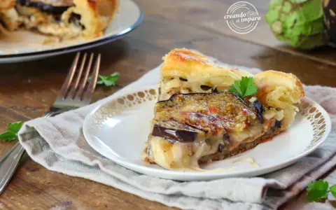 Una fetta di torta salata con melanzane, formaggio filante e pasta sfoglia dorata, guarnita con prezzemolo fresco.