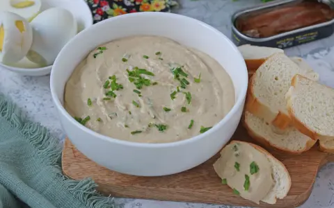 Una cremosa salsa tonnata con maionese, guarnita con erba cipollina, pronta per essere gustata con pane tostato e uova sode.