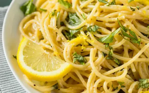 Spaghetti al limone, un classico della ricetta della Costiera Amalfitana, guarniti con scorza di limone e basilico fresco.