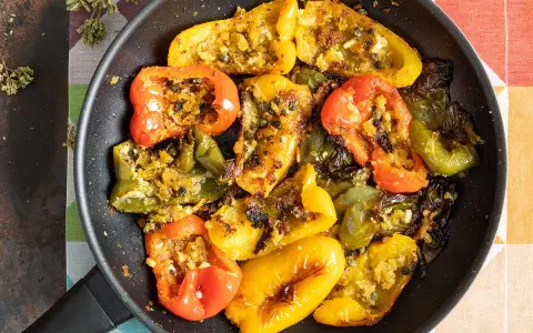 Peperoni ammollicati cotti in padella, ripieni di pangrattato e erbe aromatiche, con colori vivaci.