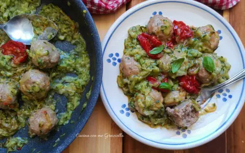 Polpette di zucchine in padella, gustose e leggere, servite con pomodorini e basilico fresco.