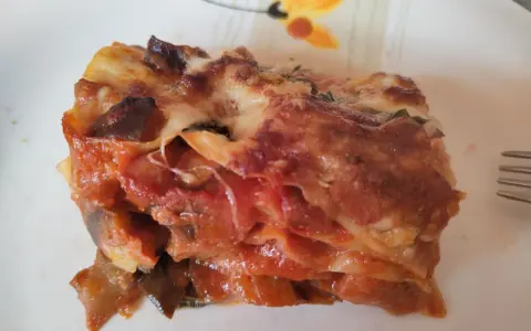 Una fetta di lasagna di melanzane, ricca e saporita, con strati di melanzane, pomodoro e formaggio filante.
