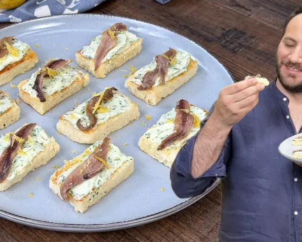 Deliziosi crostini con acciughe e robiola, guarniti con scorza di limone, pronti per essere gustati.
